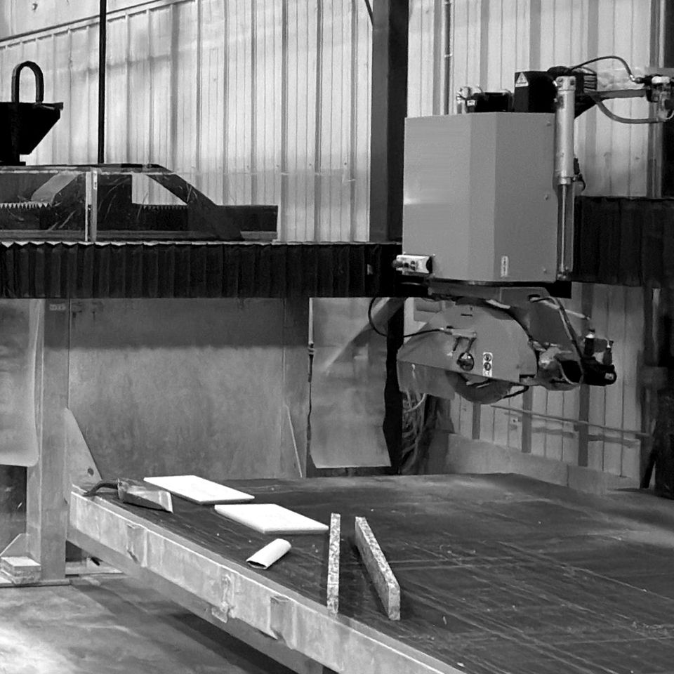 A bridge saw over its cutting table, with offcuts of stone